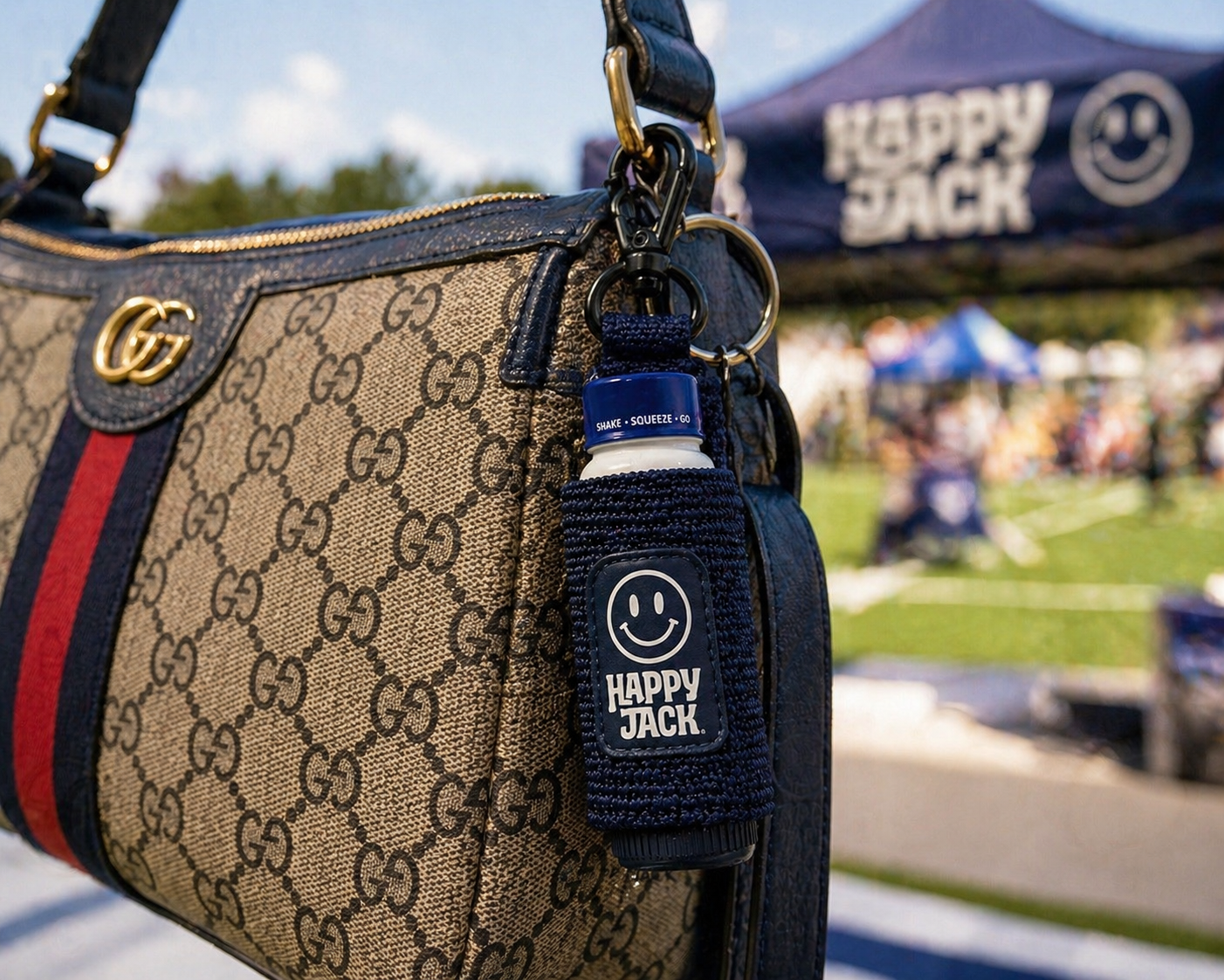 Happy Jack bottle koozie clipped to a designer bag at a tailgate